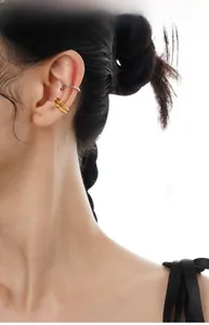 Dettaglio di ear cuff minimalisti in argento e oro a doppio strato sulla cartilagine
