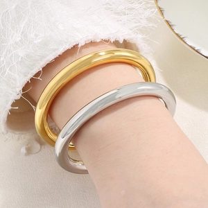 Polished titanium steel hollow tube bangles in gold and silver finishes on a wrist