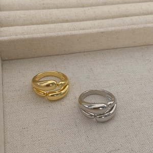 Detail shot of golden and silver double-layered teardrop rings on jewelry tray