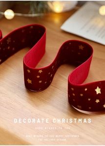 Detail of red Christmas velvet ribbon with gold stars on a festive wooden background