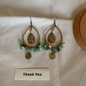 Close-up of bohemian fish-shaped shell tassel earrings on textured linen fabric background