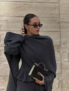 Détail du tricot gris foncé avec poignets larges et sac à main noir et doré chic