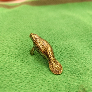 Macro shot of brass manatee figurine showcasing detailed vintage metal texture and carving