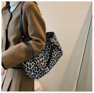 Detail of leopard print canvas tote bag with black leather strap and gold metal rings