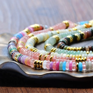 Collier en perles de pierre naturelle colorée avec entretoises dorées sur un plateau