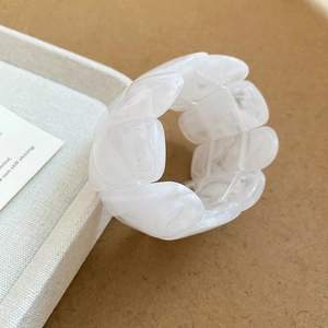 Close-up of white marble pattern acrylic wide stretch bracelet on a soft fabric display
