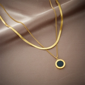 Golden double layer necklace with black Roman numeral pendant on soft silk fabric