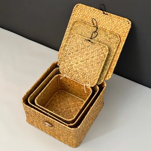 Three-piece set of natural woven grass storage boxes with lids in a 45-degree angle view