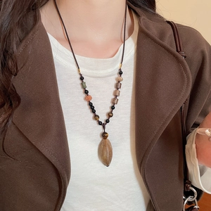 Detail of vintage beaded necklace with wooden olive pendant on braided cord