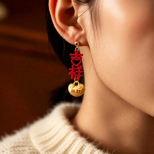 Detailed view of red Chinese lucky character earrings with gold lock charms on model