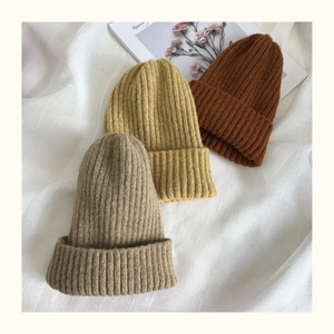 Close-up of knit beanies in grey, ginger and brown colors with vertical ribbed texture