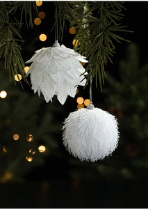 Detail of white feather and plush foam Christmas balls hanging on tree branches