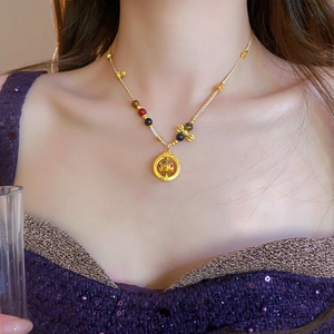 Detail showing an ethnic-style gold-plated necklace with a hollow pendant and colored beads