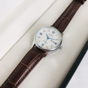 Detail showing white dial with Roman numerals and leather strap in a premium gift box