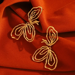 Macro view of gold plated abstract floral earrings on a luxury red velvet background