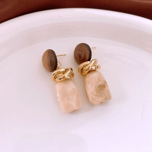 Detail of vintage geometric wood and resin drop earrings on a minimalist white tray