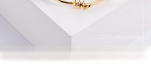 Detail shot of golden knotted twisted rope bracelet on a minimalist white geometric stand