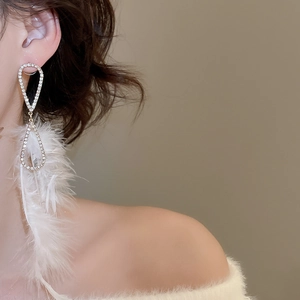 Detailansicht eleganter langer Quastenohrringe mit weißen Federn und glitzernden Diamanten