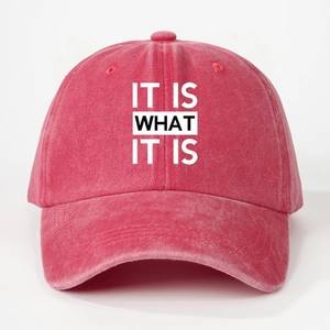 Detail view of the washed red cotton baseball cap with IT IS WHAT IT IS printed slogan