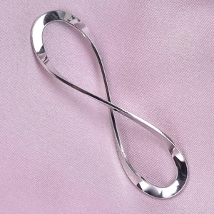 Macro shot of silver infinity pendant on pink fabric, highlighting polished 304 steel texture