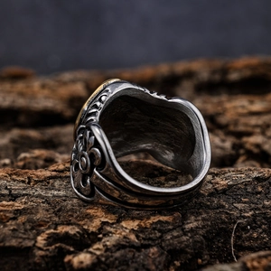 Vintage silver and gold cross ring on wood bark background with baroque engravings