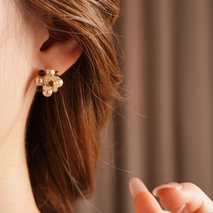 Detail of flower earrings with white pearls and brown tiger eye stones on a model