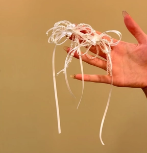 Dettaglio di una collana con fiocco in raso bianco, perle e cristalli eleganti.