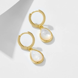 Macro detail of gold-plated hoop earrings featuring pear-shaped white mother of pearl drops