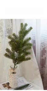 Detail of lifelike PE pine branches in a glass vase with white woven decor for Christmas