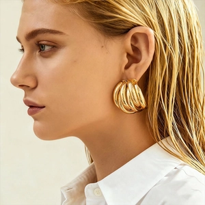 Detail of a model wearing a gold multi-layer woven geometric earring with a metallic finish