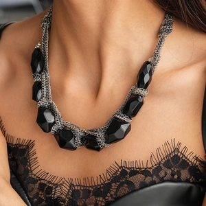 Gros plan de perles acryliques facettées noires et de la chaîne tressée gris argenté du collier