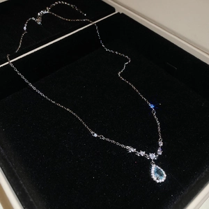 Detail of silver waterdrop pendant necklace with blue gemstone in black velvet gift box
