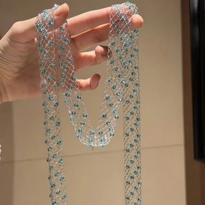 Detailed close-up of silver mesh long necklace with sky blue faceted glass crystal beads