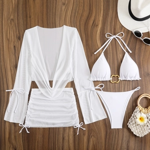 Detailed flat lay of white four-piece bikini set with mesh cover-up and golden heart ring