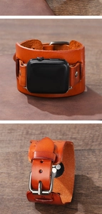 Macro shot of wide orange-brown leather watch band with metallic buckle on wood background