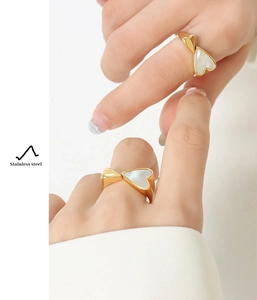 Detail of 18K gold plated heart ring with white shell inlay worn on a model's finger