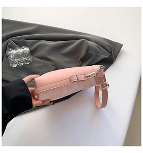 Detail of pink bucket bag featuring delicate white floral vine embroidery and silver buckles