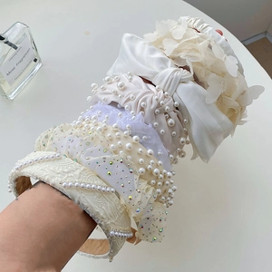 Detail of elegant pearl, lace bow, and floral headbands displayed in a soft beige theme