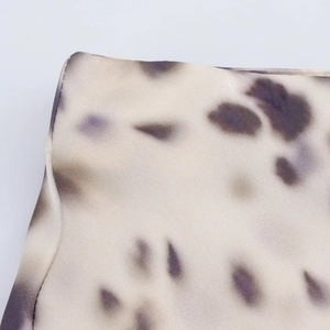 Macro view of satin fabric texture with irregular purple spots and fine hem stitching