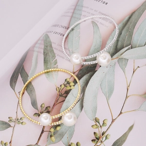Detail shot of open gold and silver bracelets featuring pearls and pavé rhinestones