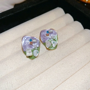 Detail of vintage enamel earrings with pearls and crystals in a beige jewelry box