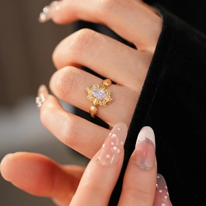 Nahaufnahme des Vintage-Gold-Blumenrings mit ovalem lila Stein am Finger der Frau