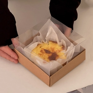 Close-up of Basque cheesecake in a transparent box with a natural brown kraft base