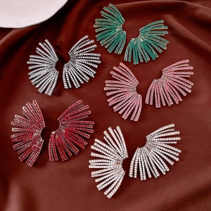 Vue à plat de boucles d'oreilles en strass en forme d'éventail sur tissu rouge texturé