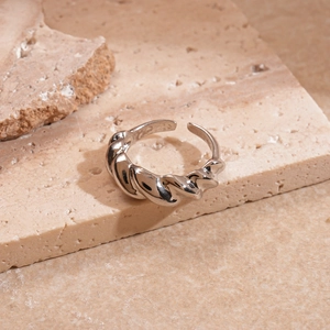 Macro shot of silver croissant style twisted ring on textured stone surface with side lighting