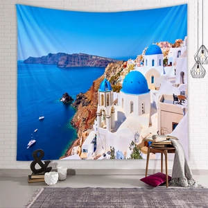 Tapestry featuring Santorini blue dome church displayed on a white brick wall in a cozy room