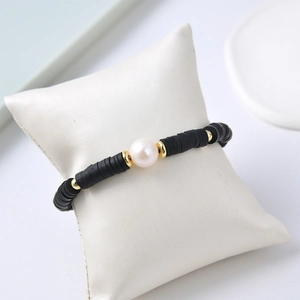 Hip hop freshwater pearl bracelet with black beads and gold accents on a white display pillow