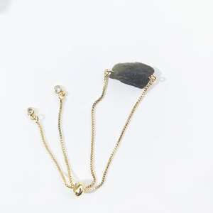 Detail of adjustable gold box chain bracelet with raw grey crystal and slider clasp