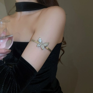 Sparkling butterfly arm cuff worn by a model in black dress, showcasing elegant luxury style