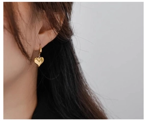 Close-up of model wearing glossy gold heart drop earrings in a French vintage style